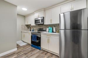 卡爾加里的住宿－Modern 2 bedroom basement suite with kitchen and laundry，厨房配有白色橱柜和不锈钢冰箱