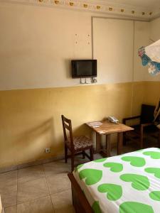 um quarto com uma cama, uma mesa e uma televisão em Gust Hotel em Bangui