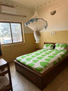 1 dormitorio con 1 cama con edredón verde y blanco en Gust Hotel en Bangui