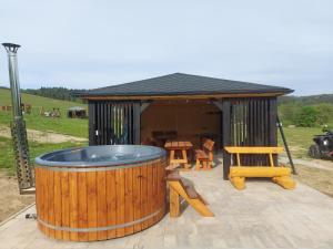 a hot tub in a gazebo with a table and chairs at Domki pod Bukowym lasem in Wańkowa