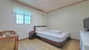 ein kleines Schlafzimmer mit einem Bett und einem TV in der Unterkunft Queen motel in Tongyeong