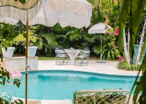 - Piscina con mesa, sillas y sombrillas en Villa Oasis Newly Remodeled Luxury Villa with Pool, en Harbour Island