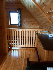 an attic room with a wooden floor and a window at Domek Tomaszne in Uścimów