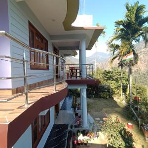 a house with a balcony with a palm tree at Barbet Homestay Kitam in Namchi