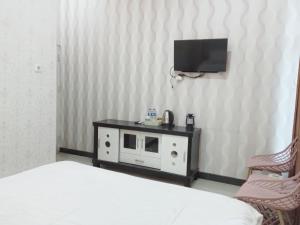 - une chambre avec un lit et une télévision murale dans l'établissement Urbanview Hotel Rifal Home Tegal, à Tegal