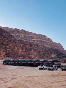 a parking lot with cars parked in front of a mountain at Sunrise Luxury Camp in Wadi Rum