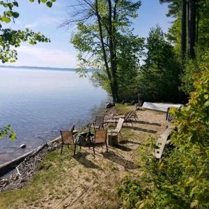 a row of chairs sitting on the shore of a lake at M22 Shores On WEST GRAND TRAVERSE BAY in Traverse City