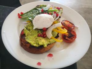 a white plate with a piece of bread with guacamole and vegetables at Hoxton Bay Surf House weligama in Weligama