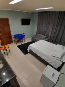 een slaapkamer met een bed en een tafel en stoelen bij suíte executiva in Divinópolis