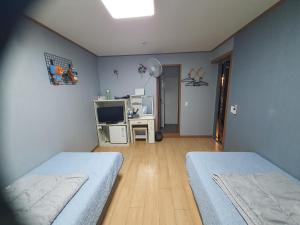 a room with two beds and a desk with a television at Ilsan Beach Daewangam Park Property in Ulsan