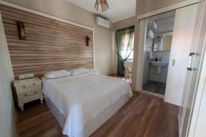 1 Schlafzimmer mit einem weißen Bett und einem Badezimmer in der Unterkunft Karina Vineyard House in Bozcaada