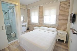 ein Schlafzimmer mit einem weißen Bett und einer Dusche in der Unterkunft Karina Vineyard House in Bozcaada