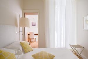een witte slaapkamer met een bed met gele kussens bij Hotel Helvetia in Sestri Levante