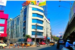 un edificio blanco alto en una calle de la ciudad con tráfico en OYO Hotel Hyderabad Heights, en Hyderabad