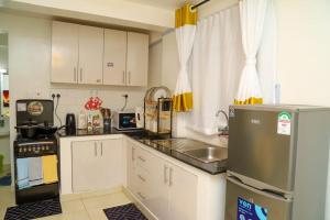 a small kitchen with white cabinets and a refrigerator at Powerground Resort in Nairobi