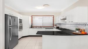 una cucina con armadi bianchi e piano di lavoro nero di Bayview House Pet Friendly , Spacious Home Accom Property a Blue Bay 