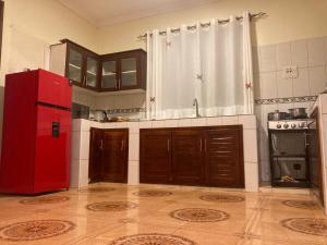 a kitchen with a red refrigerator and wooden cabinets at Jinja Airport apartment in Jinja