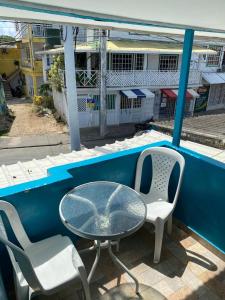 a glass table and two chairs on a balcony at Miss Titi's Native Lodge in San Andrés
