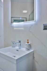 een witte badkamer met een wastafel en een spiegel bij Sea view in Sveti Juraj