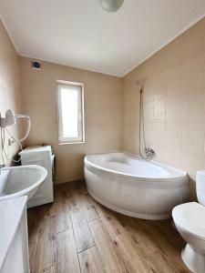 La salle de bains est pourvue d'une grande baignoire blanche et d'un lavabo. dans l'établissement N V New View, à Yaremtche