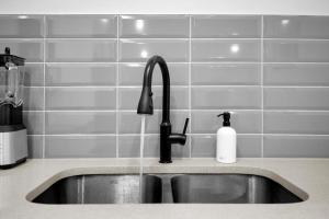 Un fregadero de cocina con un grifo y una botella de jabón. en Modern & Spacious Guest Suite, en Calgary 11 fotos más