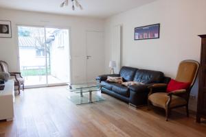 ein Wohnzimmer mit einem schwarzen Ledersofa und einem Glastisch in der Unterkunft La maison calme et lumineuse avec jardin in Toulouse