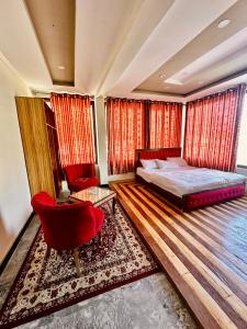 a bedroom with a bed and a red chair at Skardu Luxus Hotel in Skardu
