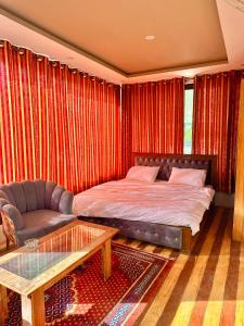 ein Schlafzimmer mit einem Bett, einem Sofa und einem Tisch in der Unterkunft Skardu Luxus Hotel in Skardu