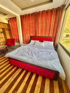 ein rotes Bett in einem Zimmer mit Fenster in der Unterkunft Skardu Luxus Hotel in Skardu