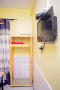 a tv on a wall with a shelf and a television on a wall at Rafiki Apartment in Zanzibar City +55 photos