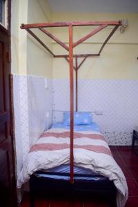 Cette chambre comprend un lit avec un cadre en bois. dans l'établissement Rafiki Apartment, à Zanzibar City
