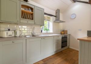Swallow Cottage في Llanerchymedd: مطبخ أبيض مع دواليب بيضاء ومغسلة