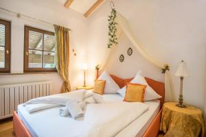 um quarto com uma cama com lençóis brancos e almofadas laranja em Ferienhaus mit Bergpanorama em Unterwössen