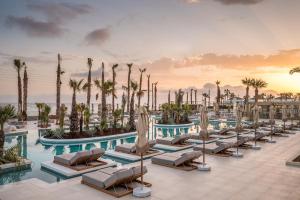 a hotel pool with lounge chairs and palm trees at Europa Beach Hotel & Spa in Hersonissos