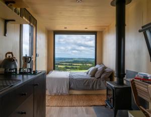 1 dormitorio con cama y ventana grande en OffGrid Tiny Home W/ View Of South Downs NP en Petersfield