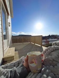 dłoń trzymająca filiżankę kawy na balkonie w obiekcie Charming house in Ulsteinvik with free parking w mieście Ulsteinvik