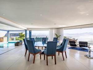 a dining room with a table and chairs and windows at Keurbooms Lagoon Villa in Plettenberg Bay