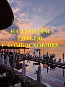 a sunset over a pool with umbrellas and the words la reporia rebuild at Club House Arkadia Beach in Odesa
