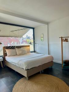 een slaapkamer met een groot bed en een groot raam bij Rembrandts Beach Suite in Zandvoort