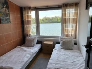 two beds in a room with a large window at Gościniec Pod Lipą in Mikołajki