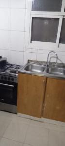 una cocina con fregadero y estufa en My Home Stay apartment 2, en Abu Dabi