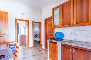 a kitchen with wooden cabinets and a sink at Comino Alto Agriturismo e Appartamenti in Capo Comino