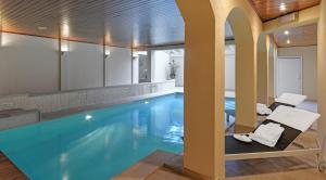 - une piscine avec 2 chaises et une table dans un bâtiment dans l'établissement Hotel Pavillon Du Zoute, à Knokke-Heist