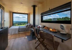 1 dormitorio con escritorio y 1 cama con ventana grande en OffGrid Tiny Home W/ View Of South Downs NP en Petersfield