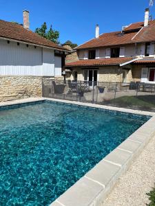 a swimming pool with blue water in front of a house at Le Saint-Hilaire in Saint-Hilaire-de-Brens