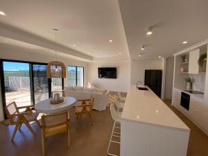 cocina y sala de estar con sofá y mesa en 27 Bluefin Cove, en Exmouth