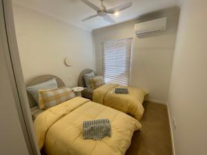two beds in a small room with a ceiling fan at 27 Bluefin Cove in Exmouth