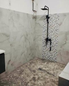 La salle de bains est pourvue d'une douche et d'un mur en marbre. dans l'établissement Mariana Guesthouse 1 in Panagsama Beach, à Moalboal