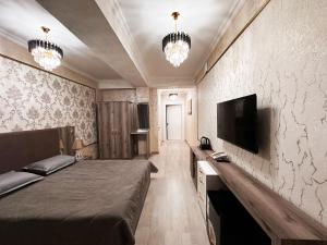 a bedroom with a bed and a flat screen tv at Stela Hotel in Shymkent