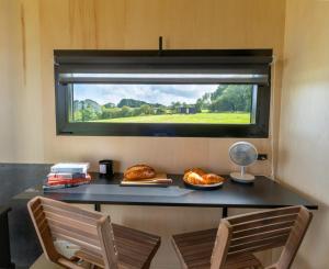 a table with two chairs and a window with food on it at OffGrid Tiny Home W/ View Of South Downs NP in Petersfield